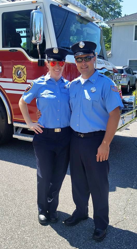two police officers smiling in front of a firetruck